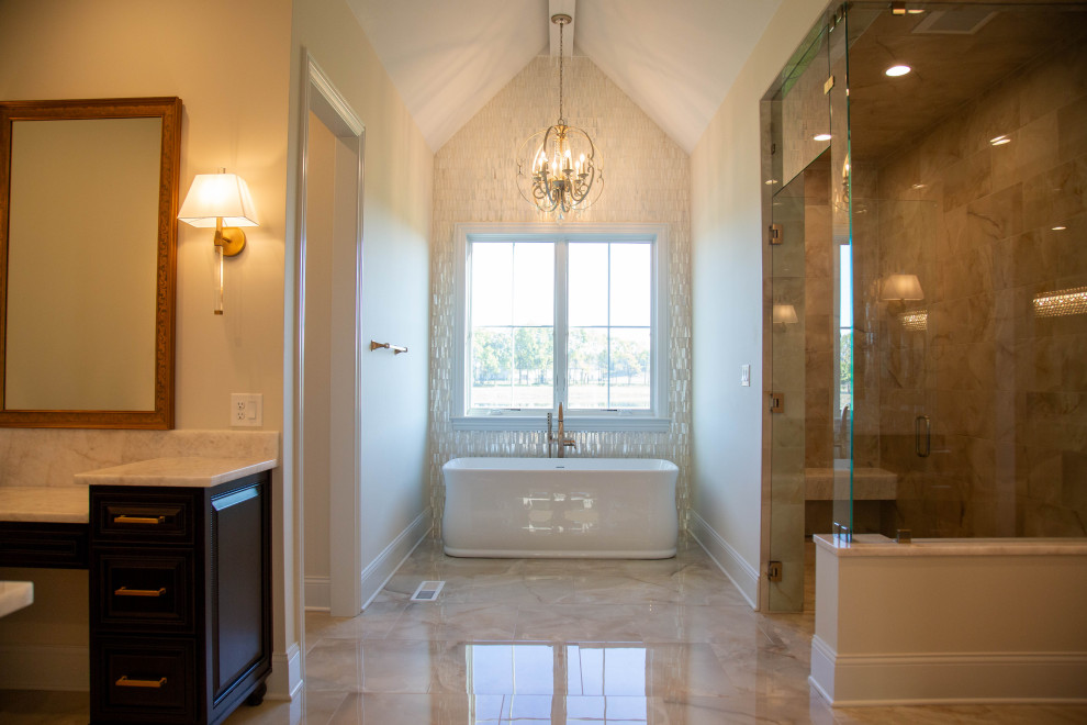 This is an example of an expansive classic ensuite bathroom in Indianapolis with raised-panel cabinets, dark wood cabinets, a freestanding bath, an alcove shower, a two-piece toilet, white tiles, glass tiles, beige walls, marble flooring, a submerged sink, granite worktops, multi-coloured floors, an open shower, beige worktops, a laundry area, double sinks and a freestanding vanity unit.