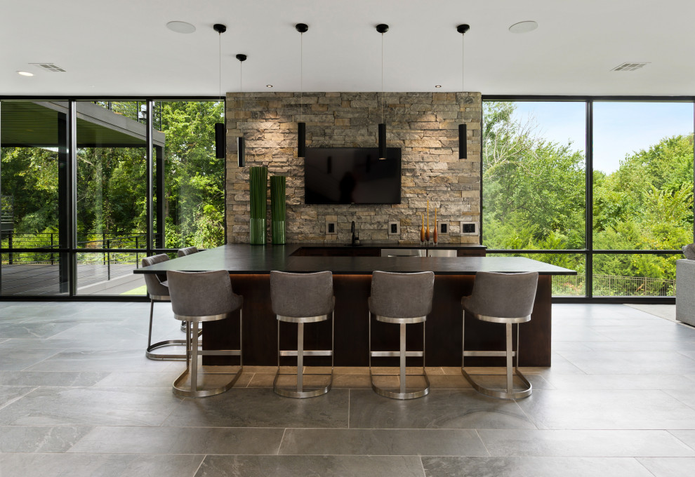 This is an example of a contemporary u-shaped seated home bar in Kansas City with stone tile splashback, grey floor and black benchtop.
