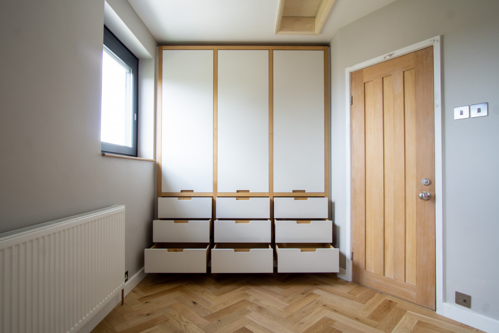 Diseño de dormitorio principal nórdico de tamaño medio con paredes grises y suelo de madera clara