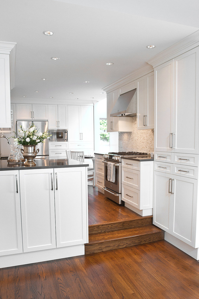Design ideas for a mid-sized arts and crafts eat-in kitchen in Vancouver with no island, shaker cabinets, white cabinets, quartz benchtops, multi-coloured splashback, mosaic tile splashback, stainless steel appliances, an undermount sink and medium hardwood floors.