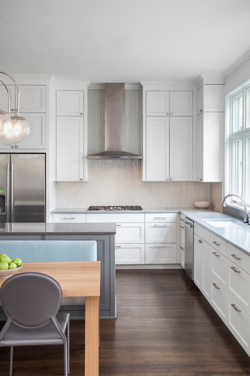 Bright kitchen with white Shaker cabinets, quartz countertops, stainless range hood, and a contrasting gray island—showcasing a clean, versatile look with strong resale appeal