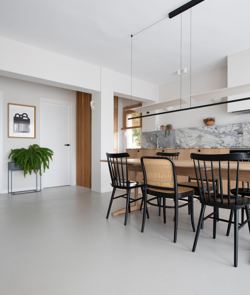 Modelo de comedor de cocina escandinavo de tamaño medio con paredes blancas, suelo de cemento, suelo gris, vigas vistas y cuadros