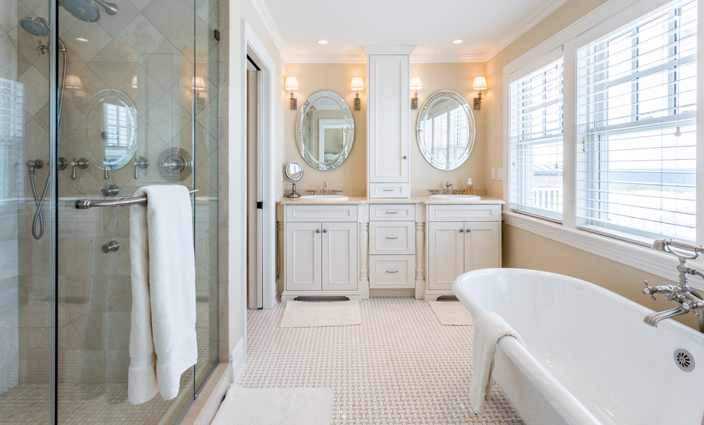 Mid-sized traditional master bathroom in New York with shaker cabinets, white cabinets, a freestanding tub, an alcove shower, beige tile, beige walls, an integrated sink, beige floor, a hinged shower door and travertine.