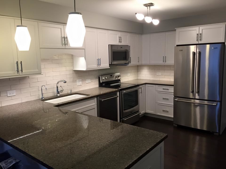 Small transitional u-shaped dark wood floor and brown floor open concept kitchen photo in Chicago with an undermount sink, shaker cabinets, white cabinets, white backsplash, subway tile backsplash, stainless steel appliances and a peninsula