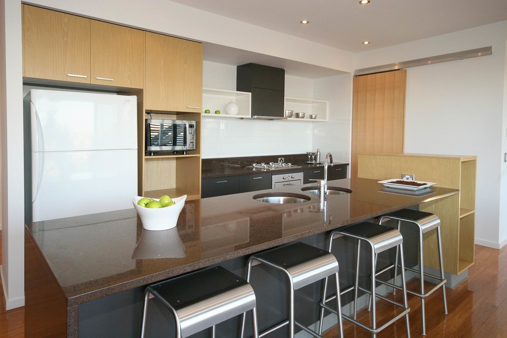 Photo of a mid-sized contemporary galley eat-in kitchen in Sunshine Coast with an undermount sink, light wood cabinets, quartz benchtops, white splashback, glass sheet splashback, stainless steel appliances, bamboo floors and with island.