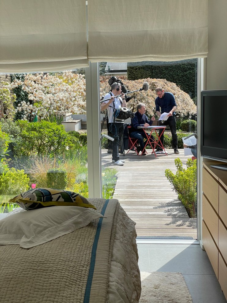Источник вдохновения для домашнего уюта: весенний регулярный сад среднего размера на заднем дворе в современном стиле с клумбами, полуденной тенью, настилом и с каменным забором