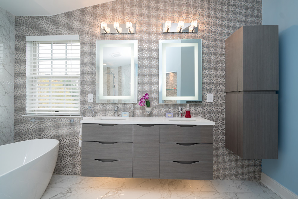This is an example of a large contemporary master bathroom in DC Metro with flat-panel cabinets, grey cabinets, a freestanding tub, multi-coloured tile, mosaic tile, blue walls, marble floors and an undermount sink.