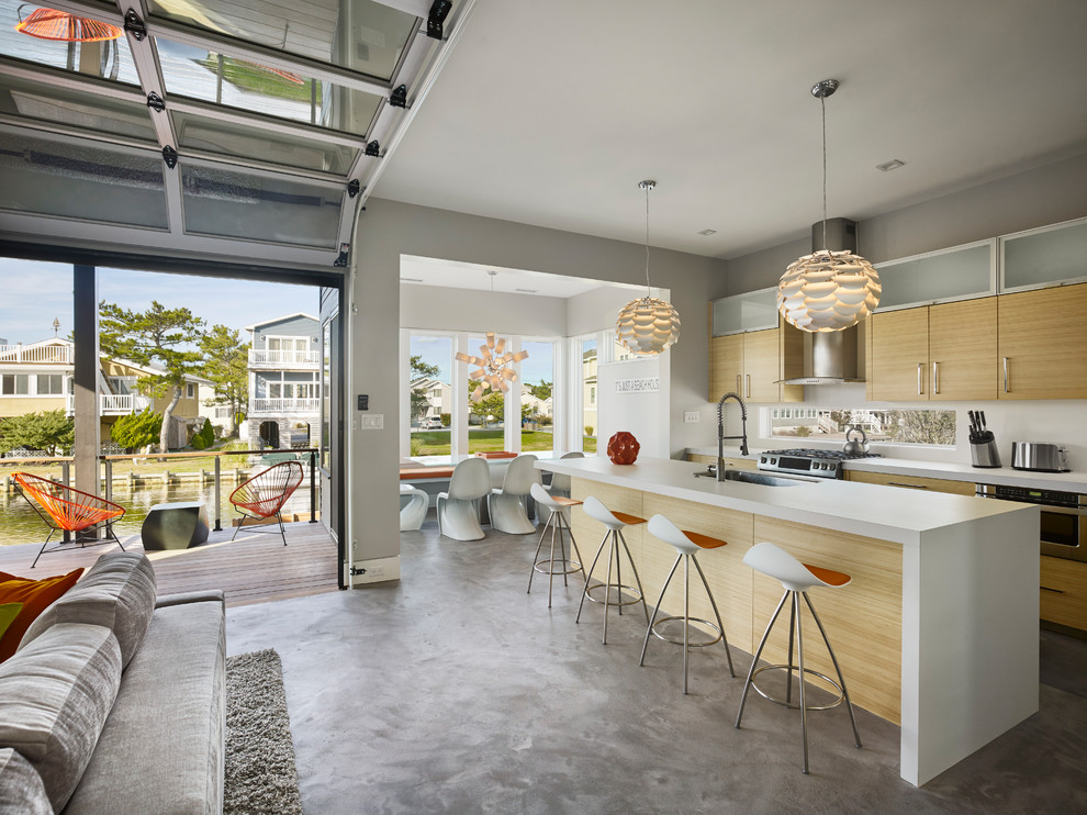 Large contemporary galley open plan kitchen in Other with an undermount sink, flat-panel cabinets, light wood cabinets, solid surface benchtops, white splashback, window splashback, stainless steel appliances, concrete floors, with island and grey floor.