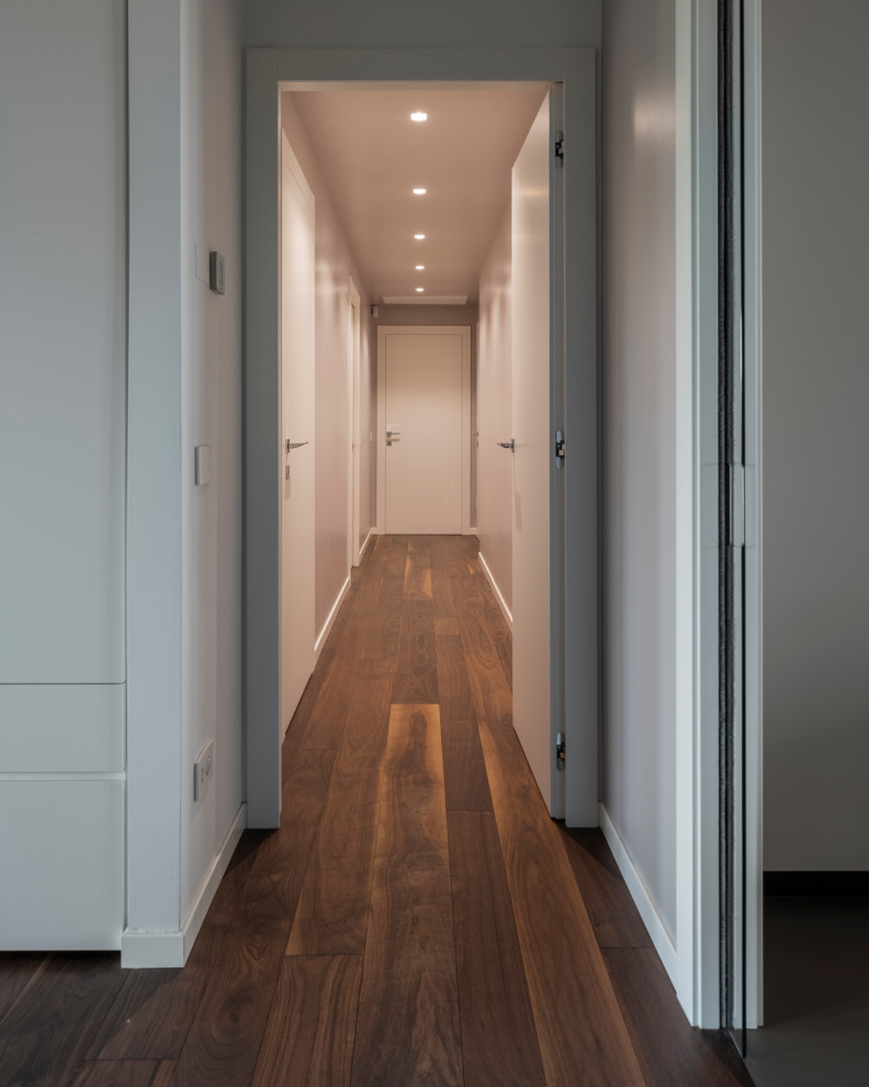 Aménagement d'un couloir moderne de taille moyenne avec un mur blanc, parquet foncé, un sol marron et un plafond décaissé.