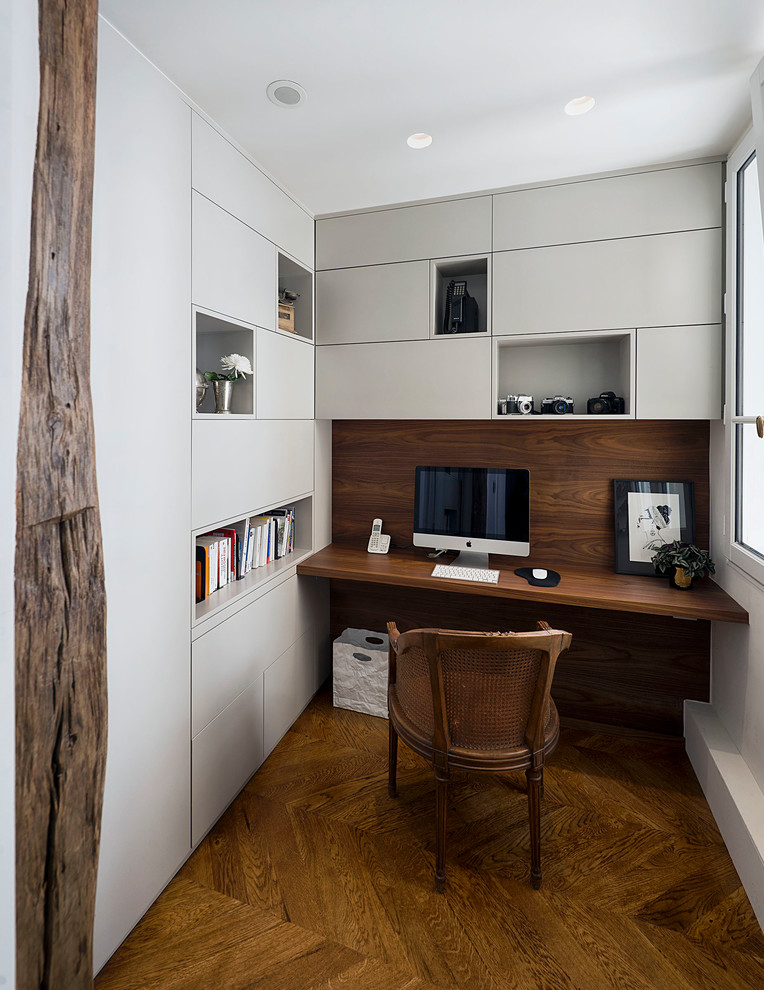 Inspiration for a large contemporary study room in Paris with dark hardwood floors, no fireplace, a built-in desk, brown floor and white walls.