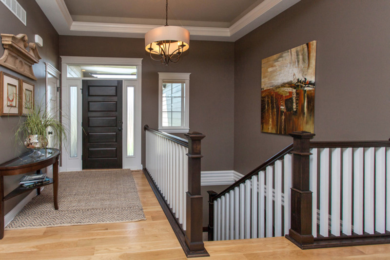 Small transitional light wood floor foyer photo with gray walls and a dark wood front door