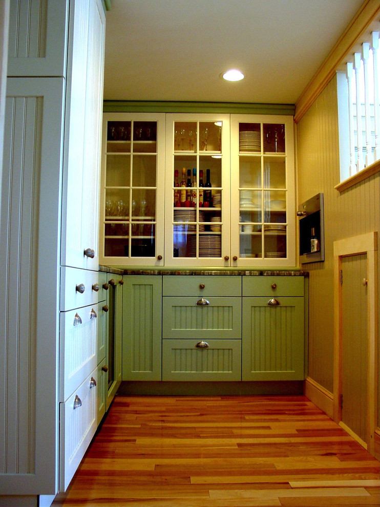 Inspiration for a small beach style l-shaped kitchen pantry in Portland Maine with glass-front cabinets, white cabinets, laminate benchtops, panelled appliances and medium hardwood floors.