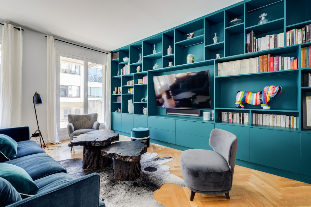 Large contemporary open concept family room in Paris with a library, blue walls, light hardwood floors, no fireplace, a wall-mounted tv and beige floor.