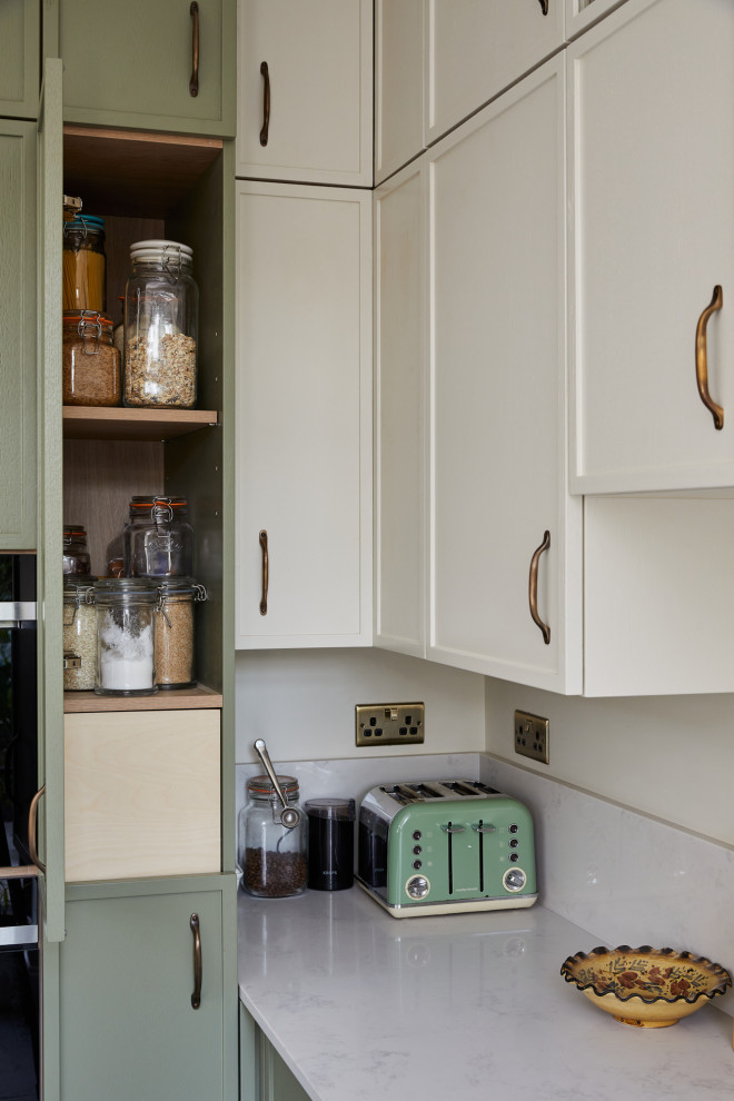 This is an example of a small transitional l-shaped separate kitchen in London with recessed-panel cabinets, green cabinets, quartzite benchtops, a peninsula and white benchtop.