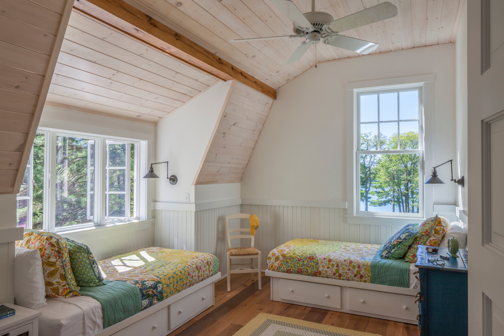 This is an example of a country guest bedroom in Portland Maine with white walls and medium hardwood floors.