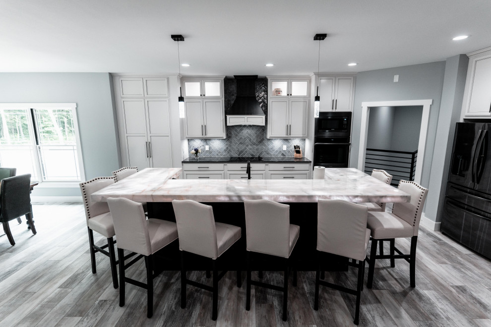 Open concept kitchen - huge transitional l-shaped laminate floor, gray floor and tray ceiling open concept kitchen idea with an undermount sink, flat-panel cabinets, white cabinets, quartz countertops, gray backsplash, ceramic backsplash, black appliances and an island
