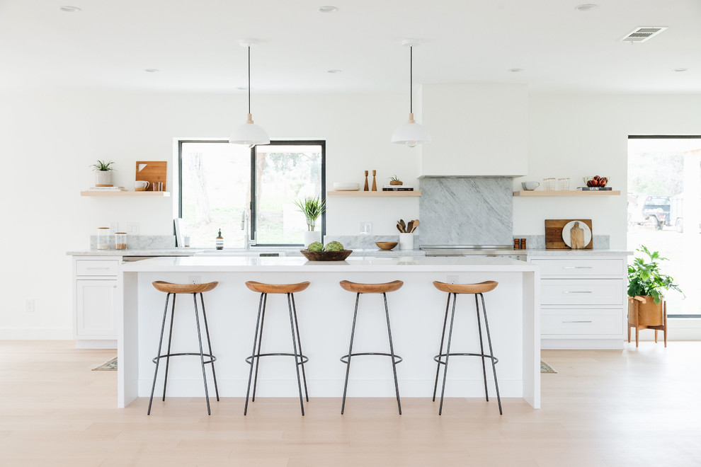 Photo of a beach style kitchen in San Diego with shaker cabinets, white cabinets, grey splashback, stone slab splashback, stainless steel appliances, light hardwood floors, with island, beige floor, grey benchtop and marble benchtops.