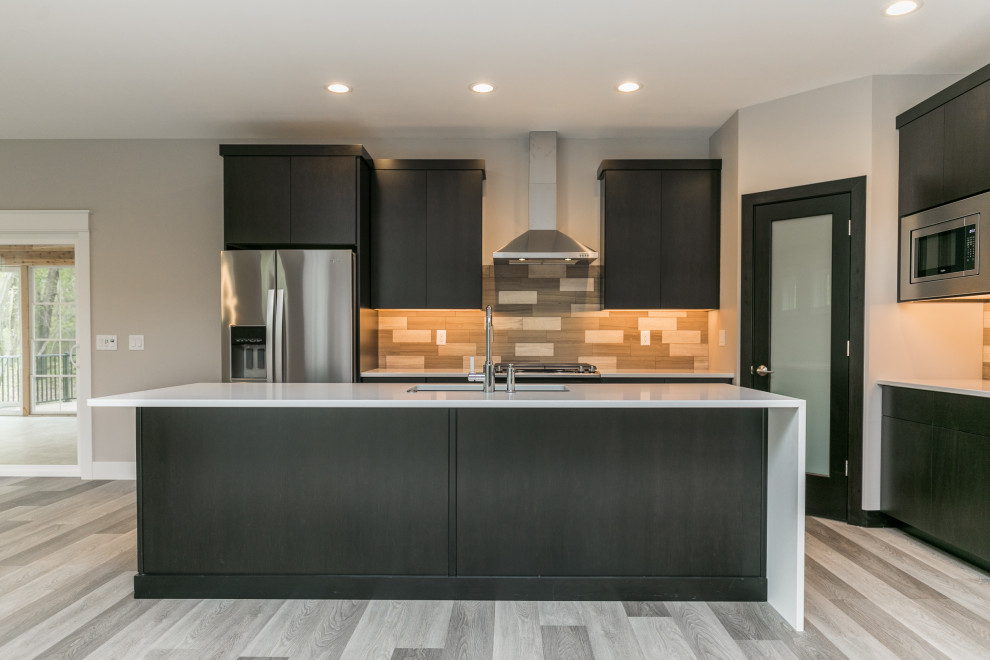 Example of a transitional galley gray floor open concept kitchen design in Cedar Rapids with flat-panel cabinets, black cabinets, beige backsplash, stainless steel appliances, an island and white countertops