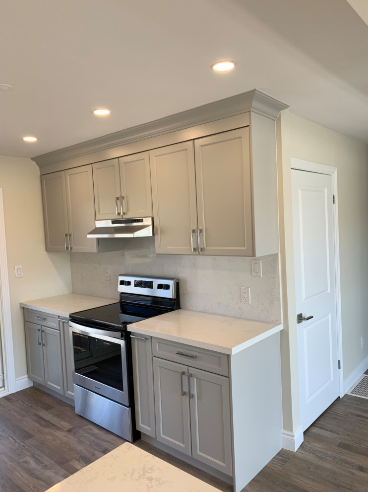 Eat-in kitchen - mid-sized transitional galley medium tone wood floor eat-in kitchen idea with an undermount sink, shaker cabinets, gray cabinets, quartz countertops, white backsplash, quartz backsplash, stainless steel appliances, a peninsula and white countertops