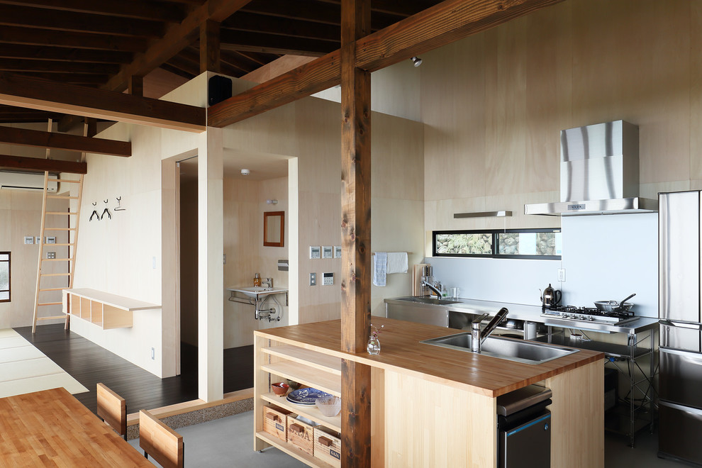 This is an example of an asian kitchen in Tokyo with open cabinets, wood benchtops, with island and grey floor.