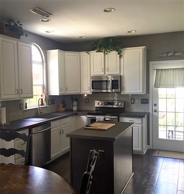 Example of a mid-sized transitional u-shaped porcelain tile eat-in kitchen design in Charlotte with an undermount sink, raised-panel cabinets, white cabinets, concrete countertops, gray backsplash, glass tile backsplash, stainless steel appliances and an island