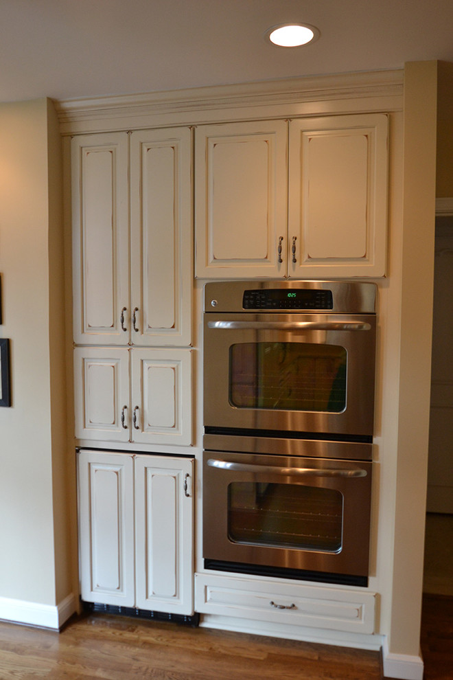 Eat-in kitchen - large transitional l-shaped medium tone wood floor eat-in kitchen idea in Columbus with an undermount sink, raised-panel cabinets, beige cabinets, granite countertops, beige backsplash, paneled appliances and an island