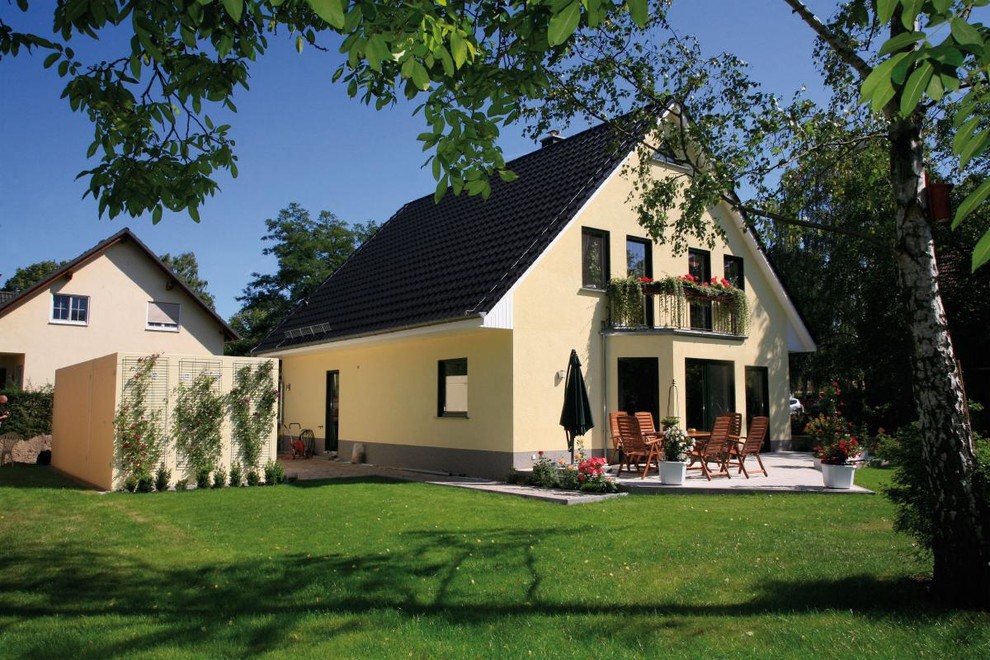 Inspiration for a mid-sized country two-storey stucco yellow exterior in Berlin with a gable roof.