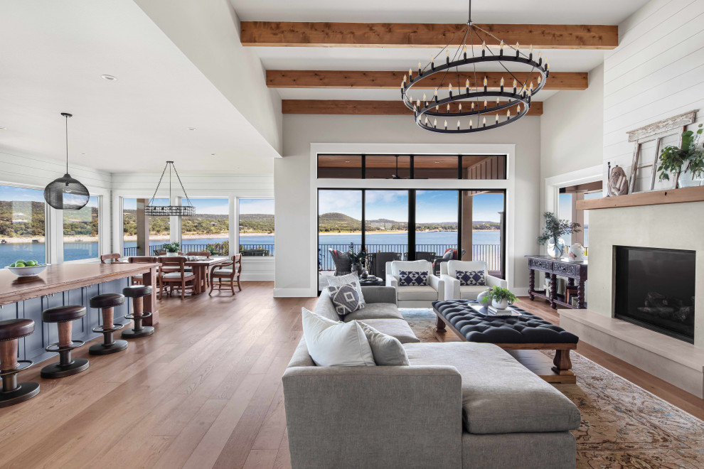 Large beach style open concept living room in Austin with grey walls, medium hardwood floors, a standard fireplace, no tv, brown floor and exposed beam.