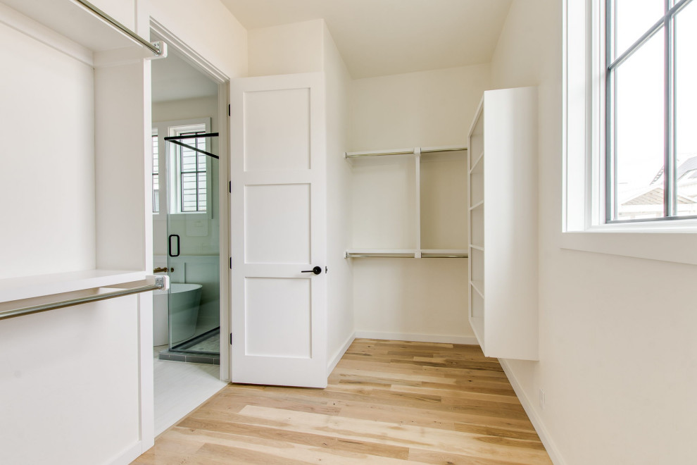 Imagen de armario vestidor unisex campestre de tamaño medio con armarios abiertos, puertas de armario blancas, suelo de madera clara y suelo beige