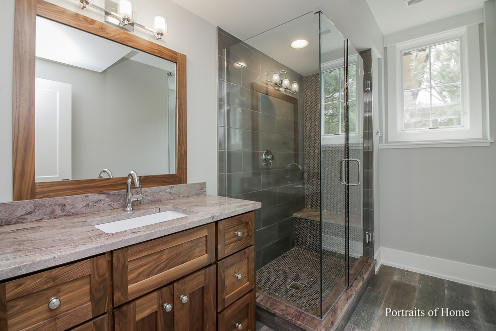 Photo of a mid-sized contemporary 3/4 bathroom in Chicago with shaker cabinets, dark wood cabinets, a corner shower, a one-piece toilet, gray tile, ceramic tile, grey walls, ceramic floors, an undermount sink, granite benchtops, black floor, a hinged shower door and pink benchtops.