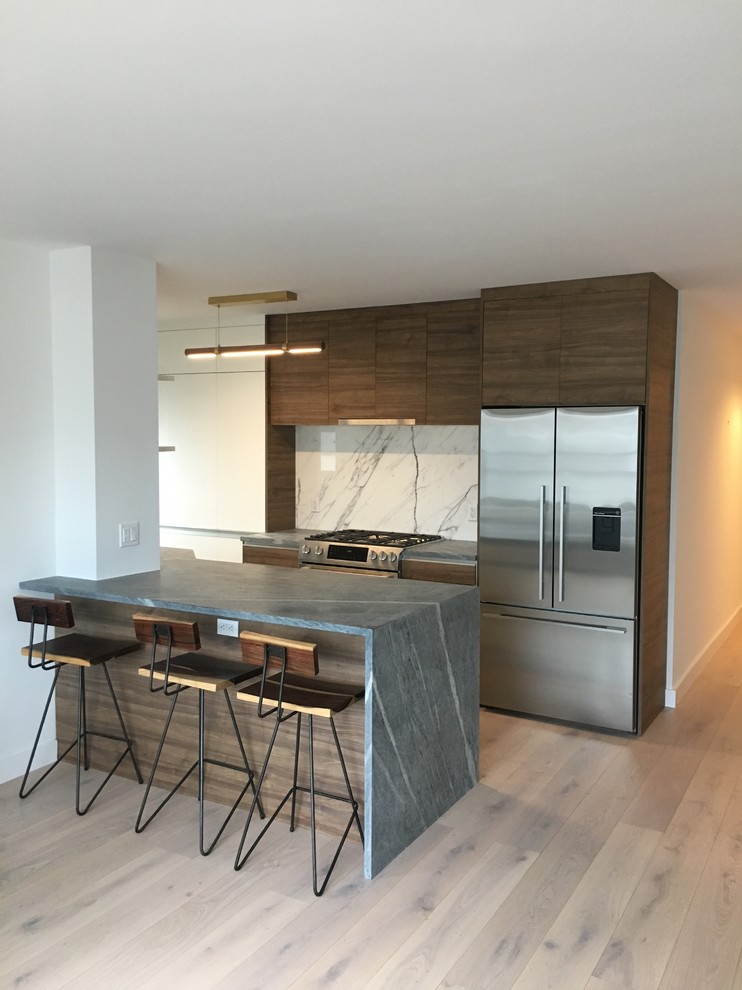 This is an example of a mid-sized contemporary u-shaped eat-in kitchen in New York with an undermount sink, flat-panel cabinets, dark wood cabinets, marble benchtops, white splashback, stone slab splashback, stainless steel appliances, light hardwood floors, with island, beige floor and grey benchtop.