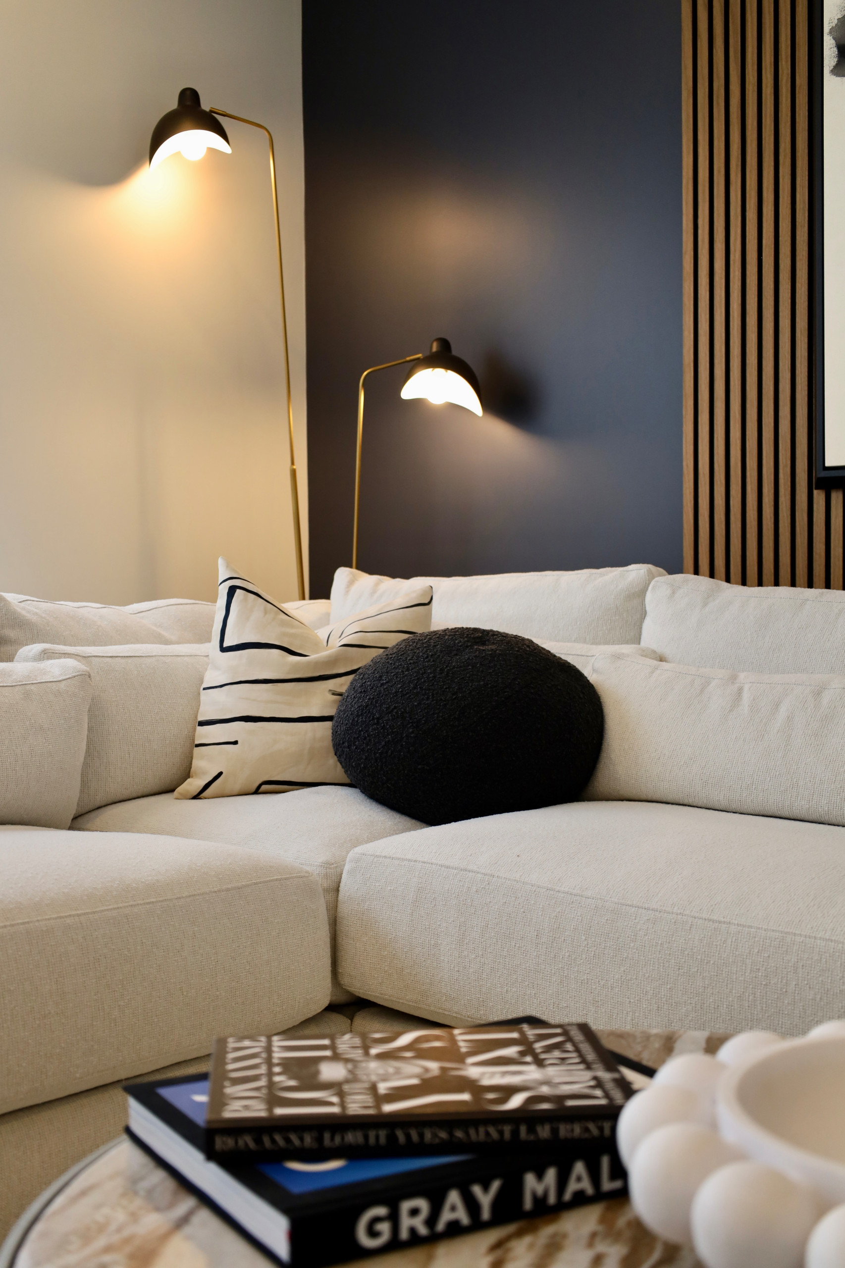 This modern luxury living room design blends clean lines, rich contrast, and layered textures to create a sophisticated yet inviting space. A custom wood slat accent wall adds architectural interest a