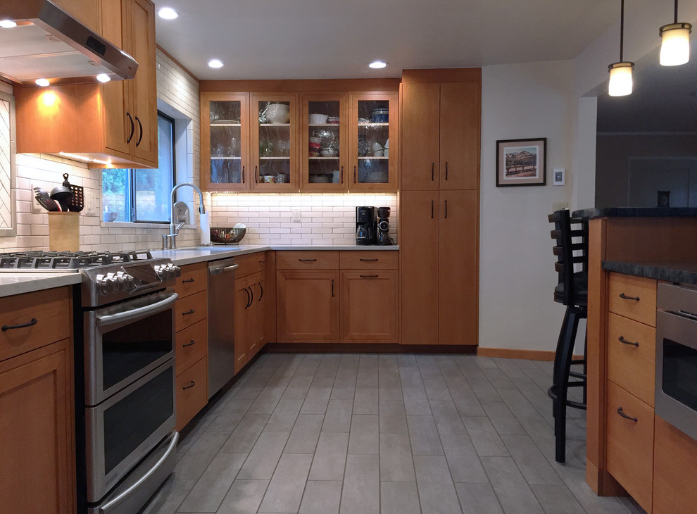 This is an example of a mid-sized midcentury galley eat-in kitchen in Other with an integrated sink, flat-panel cabinets, medium wood cabinets, soapstone benchtops, white splashback, ceramic splashback, stainless steel appliances, ceramic floors, no island and grey floor.