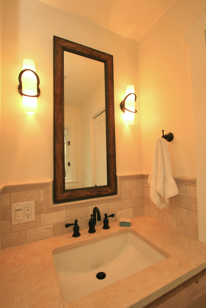 Photo of a small arts and crafts 3/4 bathroom in Other with shaker cabinets, medium wood cabinets, a two-piece toilet, beige tile, travertine, white walls, limestone floors, an undermount sink, solid surface benchtops, beige floor and beige benchtops.