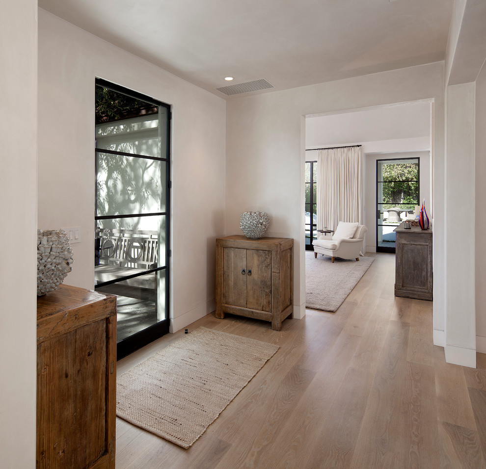 Mid-sized transitional front door in Santa Barbara with white walls, light hardwood floors, a single front door and a black front door.