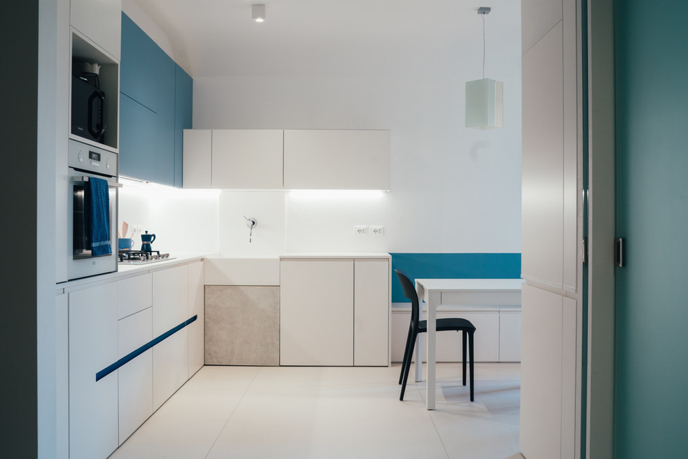 Mid-sized mediterranean l-shaped eat-in kitchen in Bologna with an integrated sink, beaded inset cabinets, white cabinets, concrete benchtops, white splashback, porcelain splashback, white appliances, porcelain floors, no island, white floor and white benchtop.