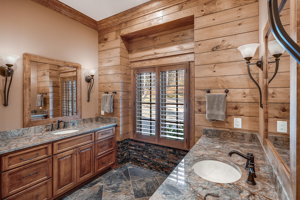This is an example of a mid-sized country 3/4 bathroom with shaker cabinets, medium wood cabinets, an alcove shower, a one-piece toilet, beige tile, beige walls, an undermount sink, multi-coloured floor, a hinged shower door and beige benchtops.