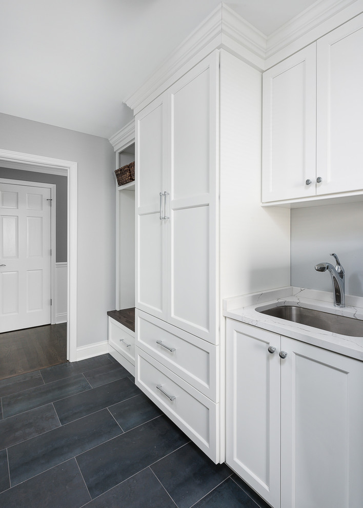 Photo of a large transitional galley utility room in Chicago with an undermount sink, white cabinets, granite benchtops, grey walls, a side-by-side washer and dryer and white benchtop.