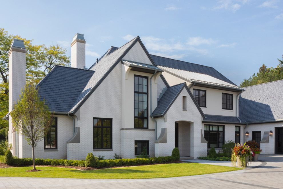 Cette photo montre une façade de maison blanche nature en brique avec un toit à deux pans et un toit noir.