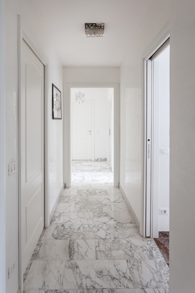 Ispirazione per un corridoio minimal di medie dimensioni con pareti bianche, pavimento in marmo, una porta a due ante, una porta bianca e pavimento grigio