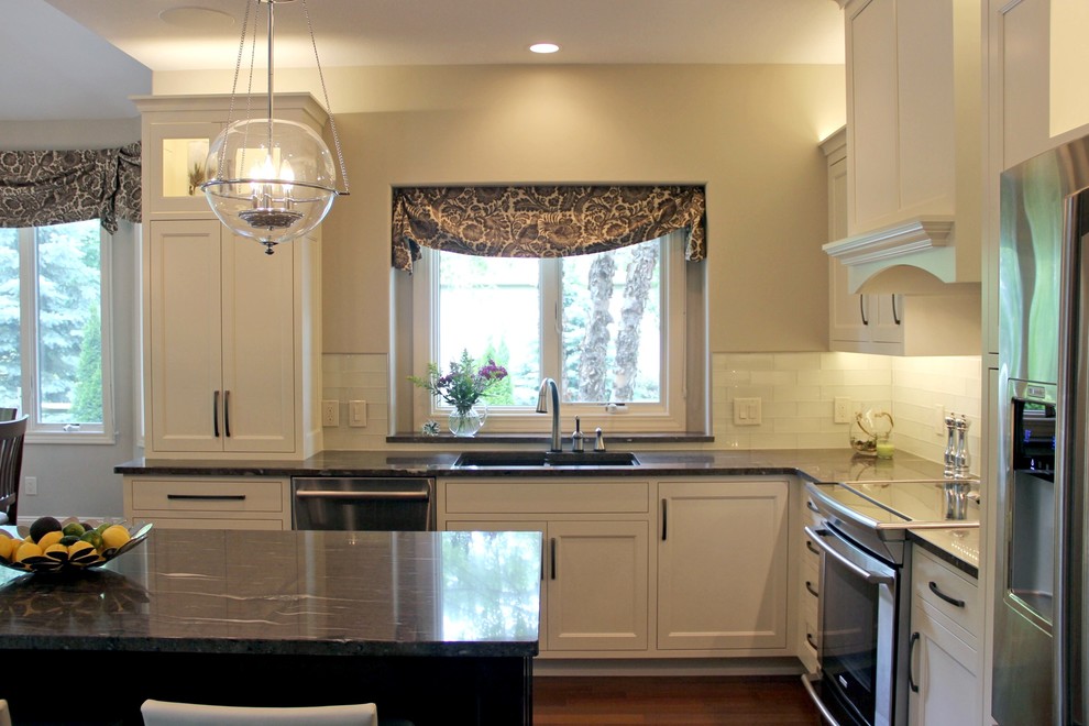 Mid-sized transitional l-shaped dark wood floor eat-in kitchen photo with a double-bowl sink, shaker cabinets, white cabinets, granite countertops, white backsplash, glass tile backsplash, stainless steel appliances and an island