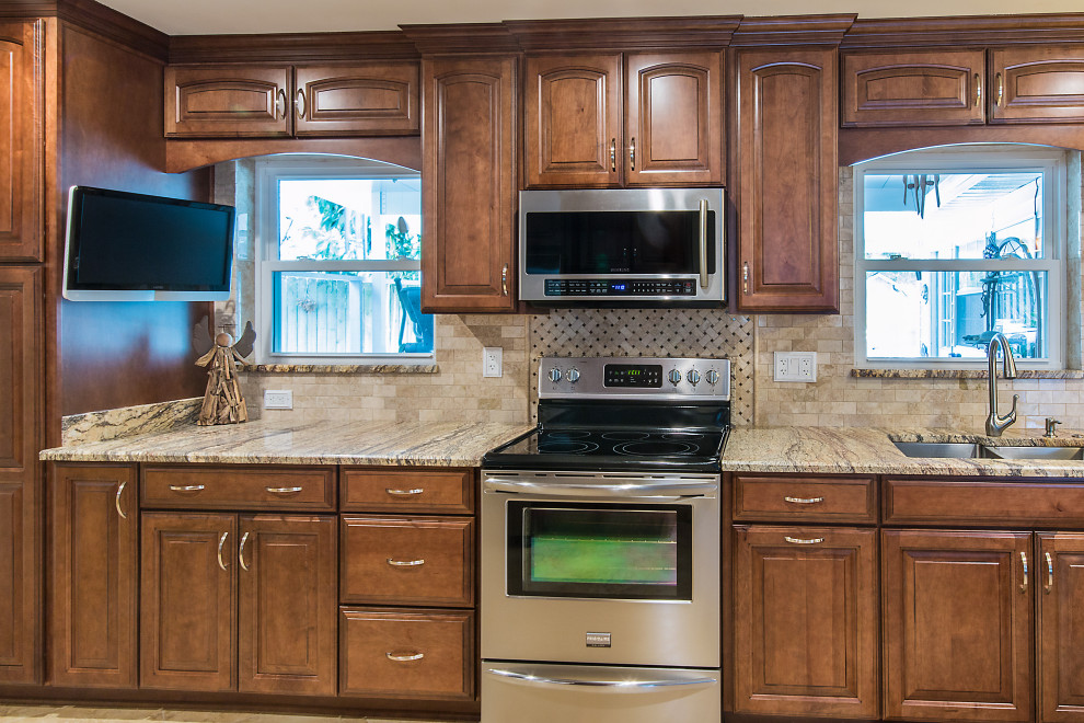 Open concept kitchen - large galley open concept kitchen idea with raised-panel cabinets, brown cabinets, granite countertops and a peninsula