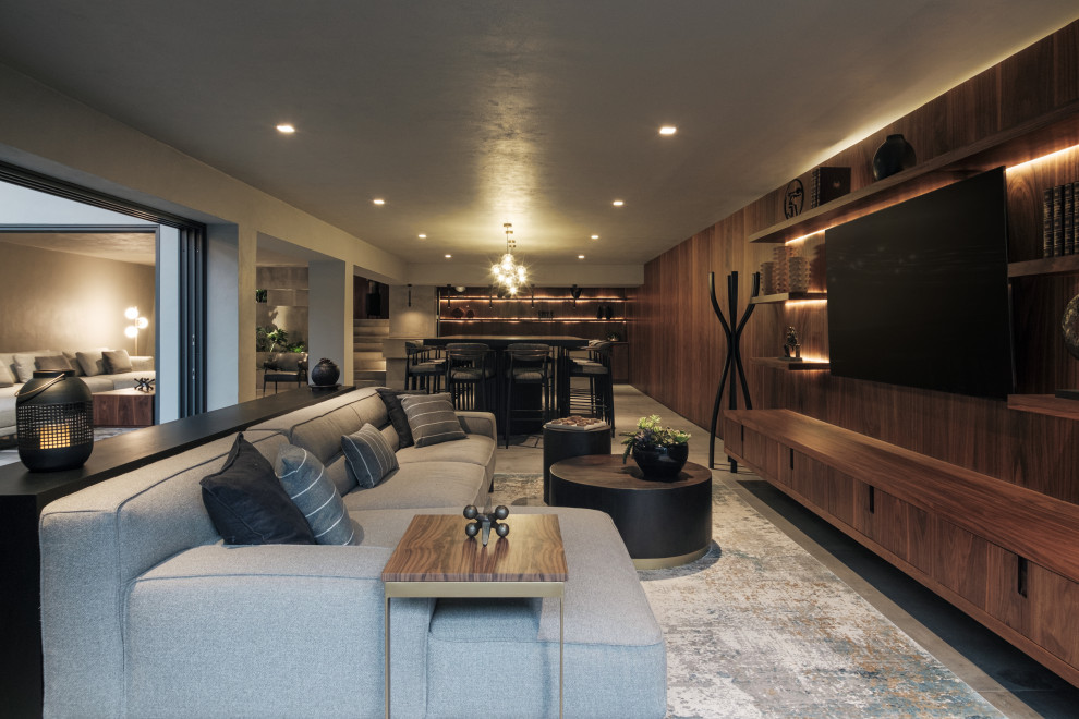 Photo of a contemporary loft-style family room in Houston with grey walls, concrete floors, a wall-mounted tv, grey floor and wood walls.