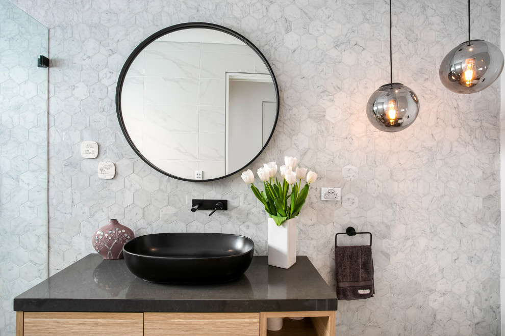 This is an example of a mid-sized contemporary bathroom in Sydney with light wood cabinets, black and white tile, marble, engineered quartz benchtops and black benchtops.