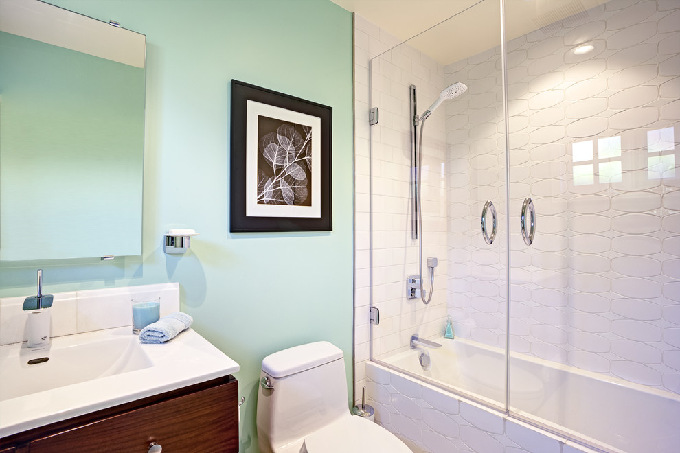 This is an example of a small contemporary bathroom in San Francisco with open cabinets, dark wood cabinets, a shower/bathtub combo, a one-piece toilet, white tile, ceramic tile, green walls, ceramic floors, an integrated sink and solid surface benchtops.
