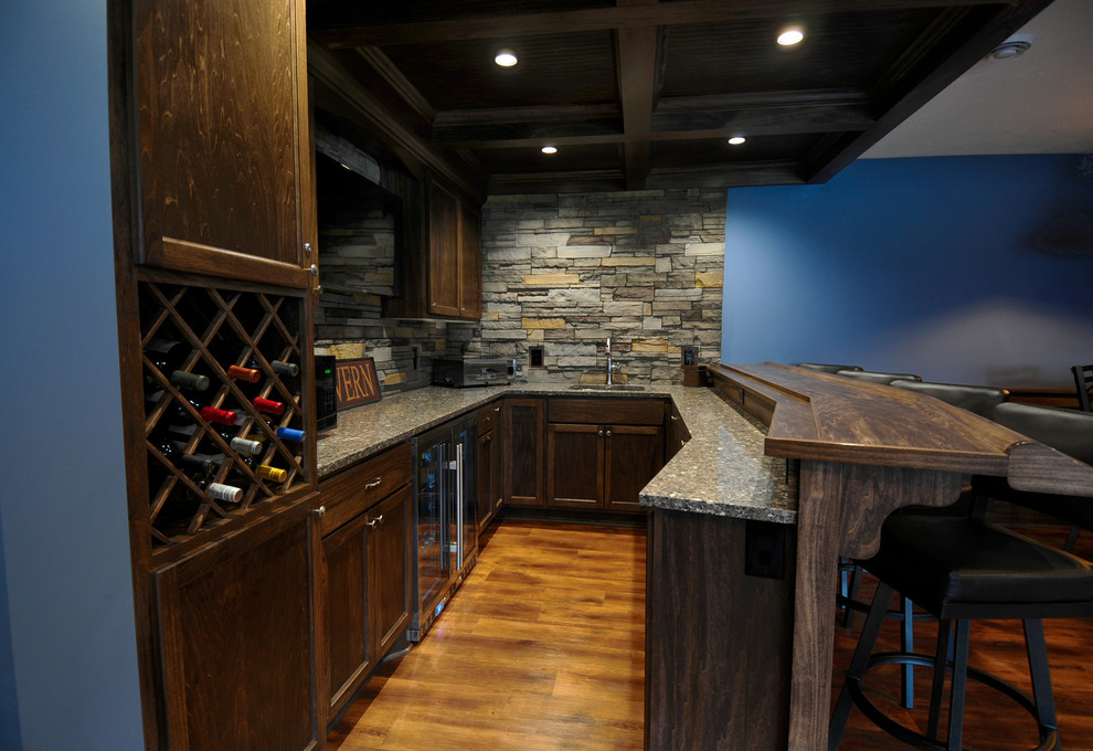 Photo of a mid-sized traditional u-shaped seated home bar in Minneapolis with an undermount sink, recessed-panel cabinets, dark wood cabinets, granite benchtops, multi-coloured splashback, stone tile splashback and vinyl floors.