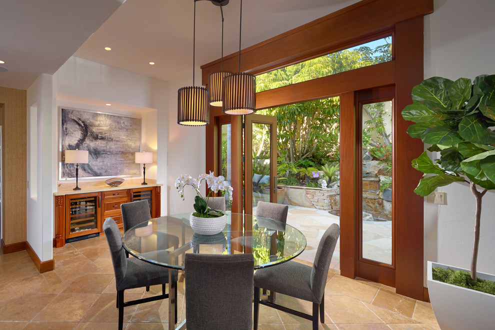 This is an example of a tropical dining room in Orange County with white walls and beige floor.