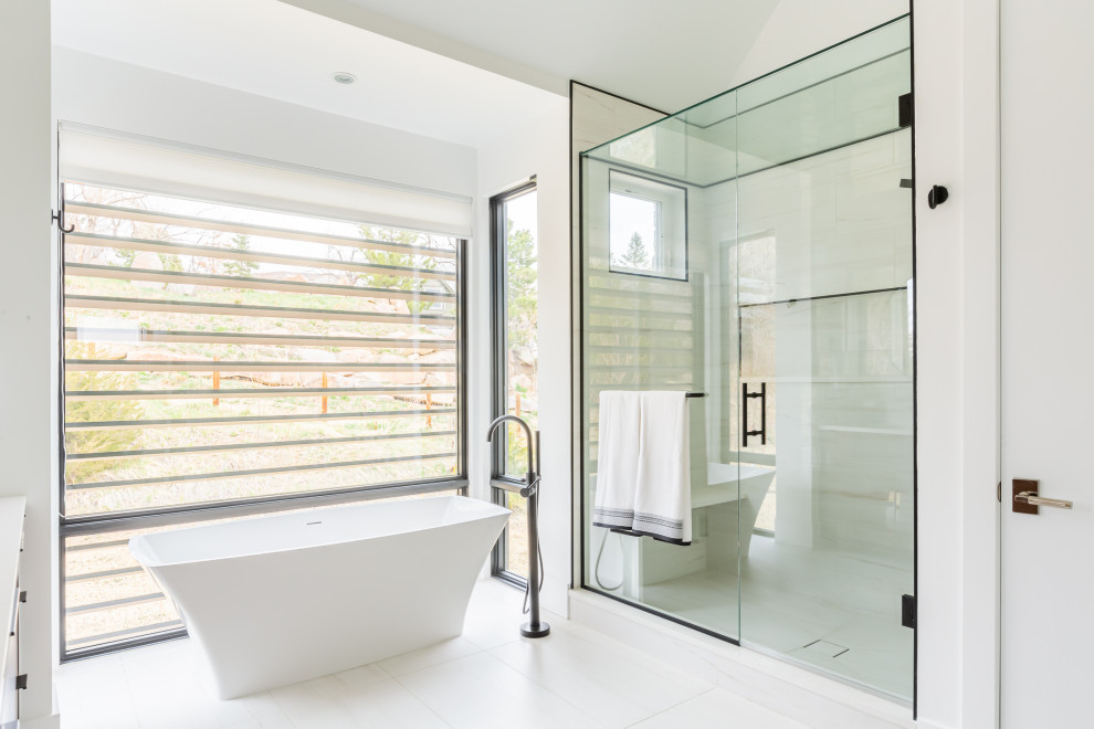 Стильный дизайн: ванная комната в стиле модернизм с отдельно стоящей ванной, душем в нише, белой плиткой, белыми стенами, душем с распашными дверями, сиденьем для душа и тумбой под две раковины - последний тренд