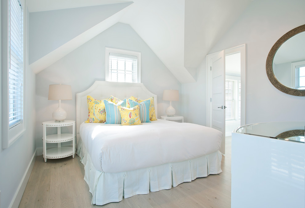 This is an example of a beach style bedroom in Boston with white walls, light hardwood floors and no fireplace.