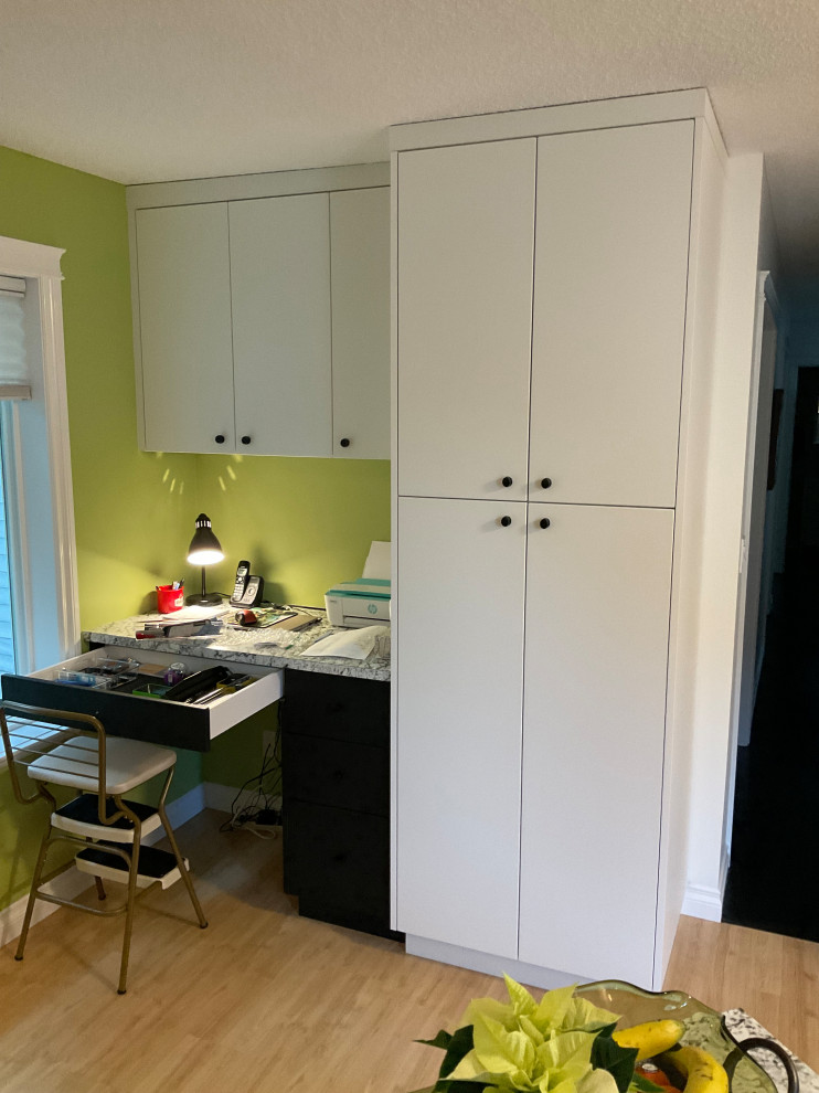 Trendy kitchen with glossy black cabinets, white backsplash, and stainless steel